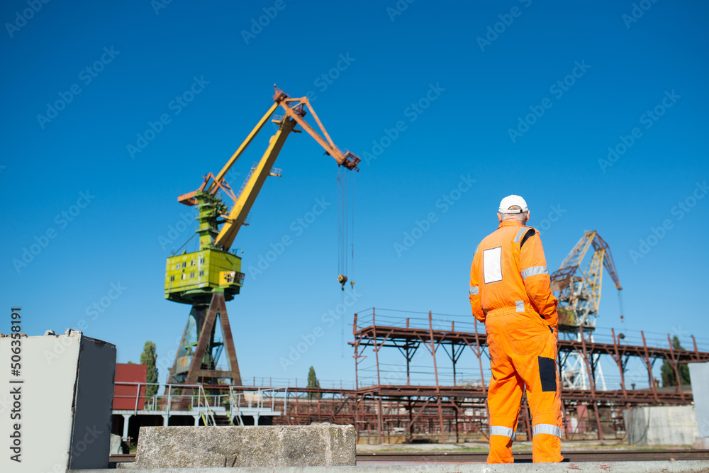 Shipyard worker in overalls in front of a crane