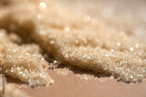 The texture of a yellow shining scrub on a beige background.
