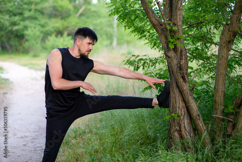 Male athlete doing leg stretching in nature, close-up