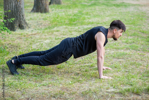 Male athlete doing push-ups from the ground on the sports ground, close-up