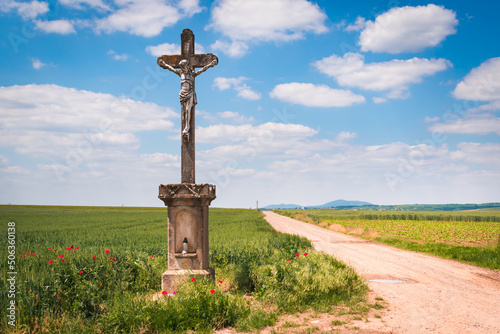 A dirt road with a cross in the hungarian countryside in summer