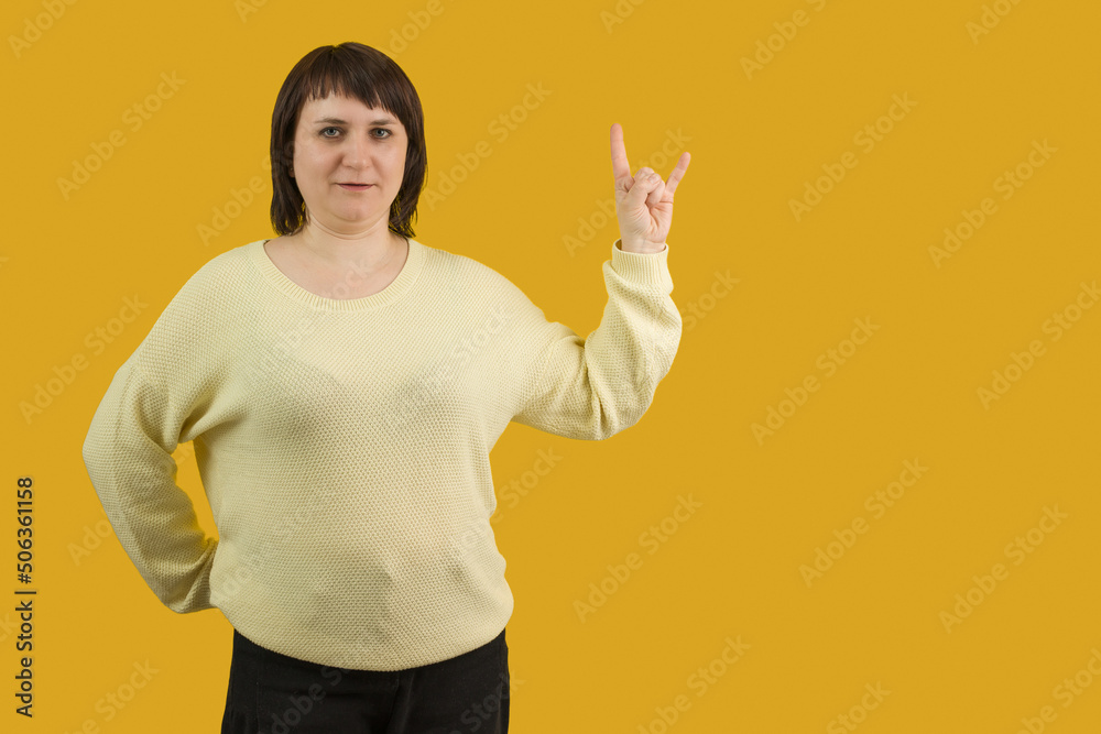 woman showing sing of the horns on yellow background woman showing sing of the horns on yellow background