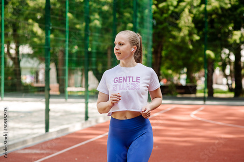 Sporty slim young woman in sportsweat running outdoors the sports ground