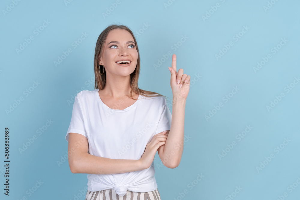 Young woman over isolated blue background thinking about an idea in white t-shirt and striped pants meditates. Cute caucasian girl smiling while dreaming and planning while standing in the studio Young woman over isolated blue background thinking about an idea in white t-shirt and striped pants meditates. Cute caucasian girl smiling while dreaming and planning while standing in the studio