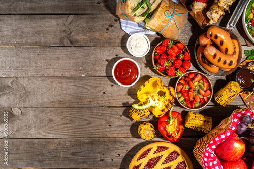 Various picnic barbeque food and drink flatlay. Summer bbq picnic food, assorted grilled meats, kebabs, vegetable, fruit salad, traditional picnic summer pie cake, sandwiches, top view copy space