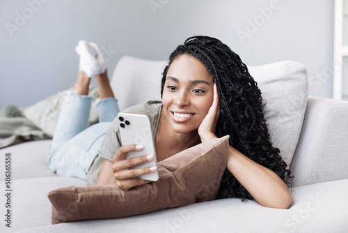 Young woman using smartphone at home. Student girl texting on mobile phone in her room. Communication, home work or study, connection, mobile apps, technology, lifestyle concept