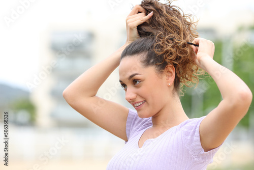 Happy woman doing ponytail in the street