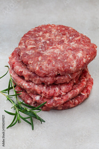 Raw free range 100% beef burger patties on mottled grey with copy space
