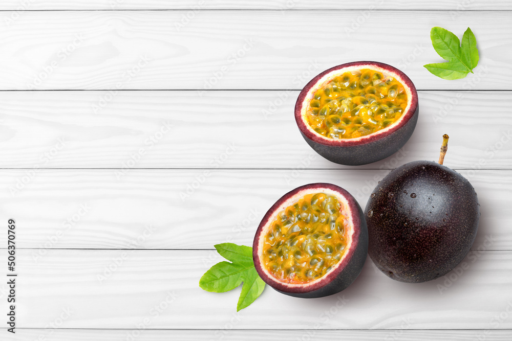 Passion fruit with green leaf and cut in half sliced isolated on white wood background. Top view. Flat lay. Copy space for text. Passion fruit with green leaf and cut in half sliced isolated on white wood background. Top view. Flat lay. Copy space for text.