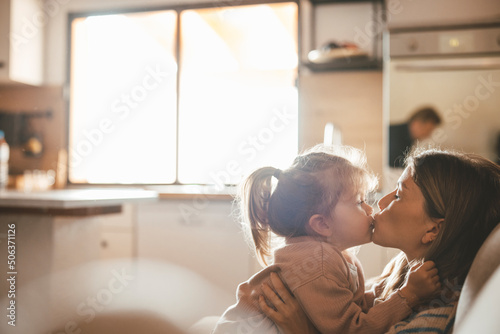 Young woman kissing daughter at home
