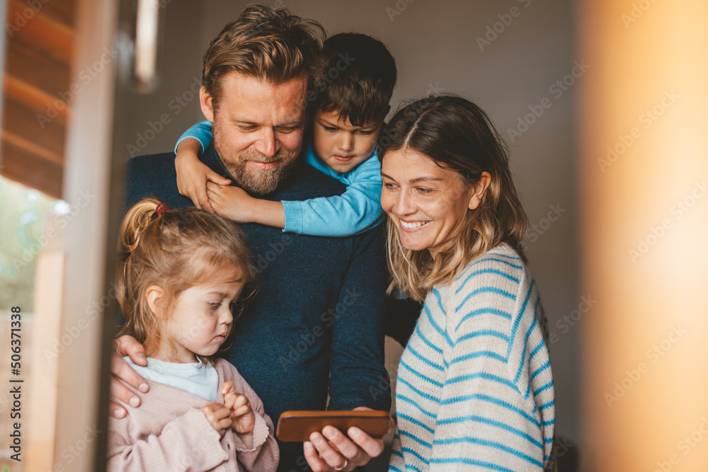 Happy man sharing smart phone with family seen through window Happy man sharing smart phone with family seen through window