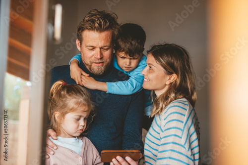 Mature man sharing smart phone with family seen through window photo