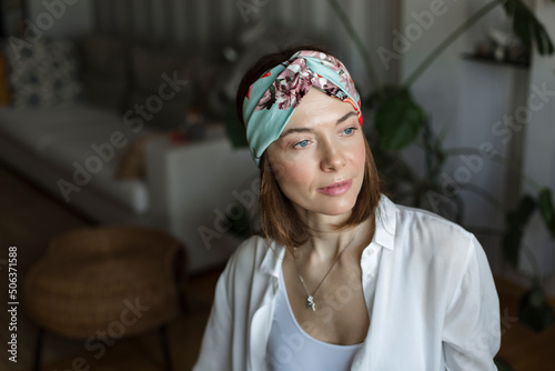 Thoughtful mature woman wearing headband sitting in living room at home