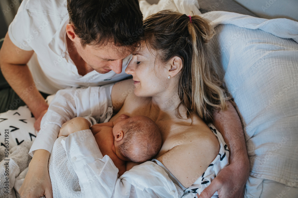 Father embracing woman and son lying on bed at home Father embracing woman and son lying on bed at home
