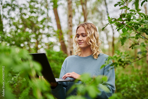 Smiling freelancer working on laptop in woodland photo