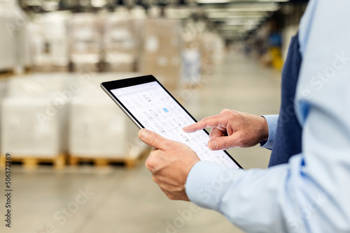 Hands of manager checking list through tablet PC in warehouse photo
