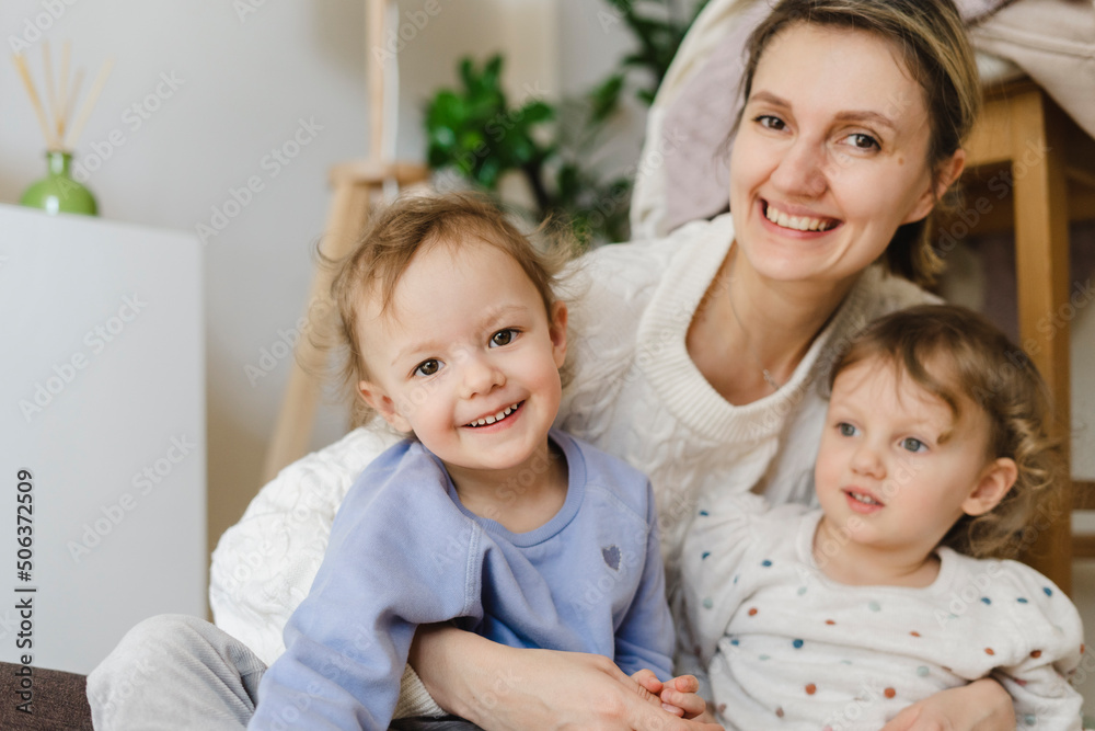 Happy mother with twin daughters sitting in living room Happy mother with twin daughters sitting in living room
