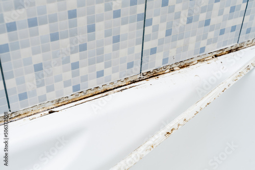 Dirty tiles in a bathroom shower with sealant covered in mould and mildew photo