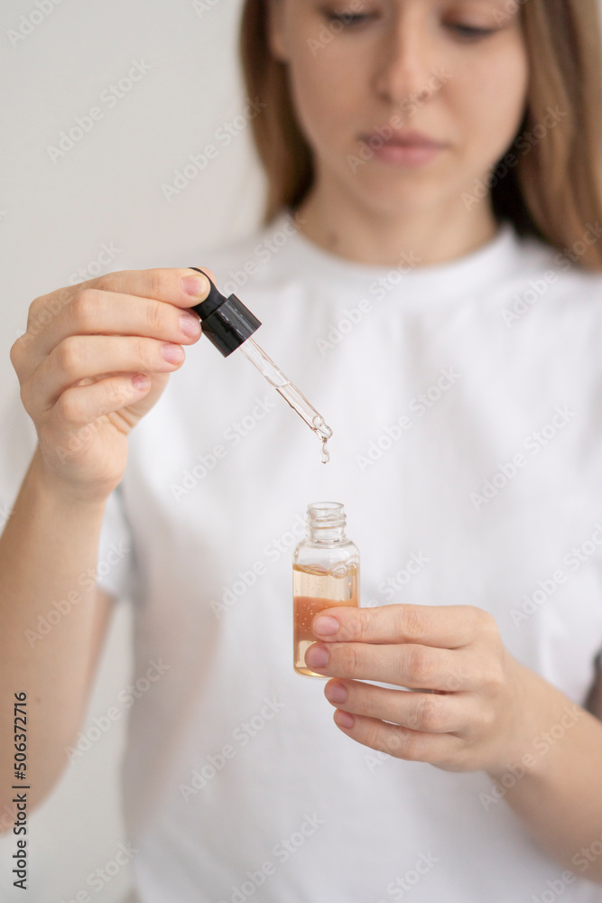 Young woman pouring drop in essential oil bottle Young woman pouring drop in essential oil bottle