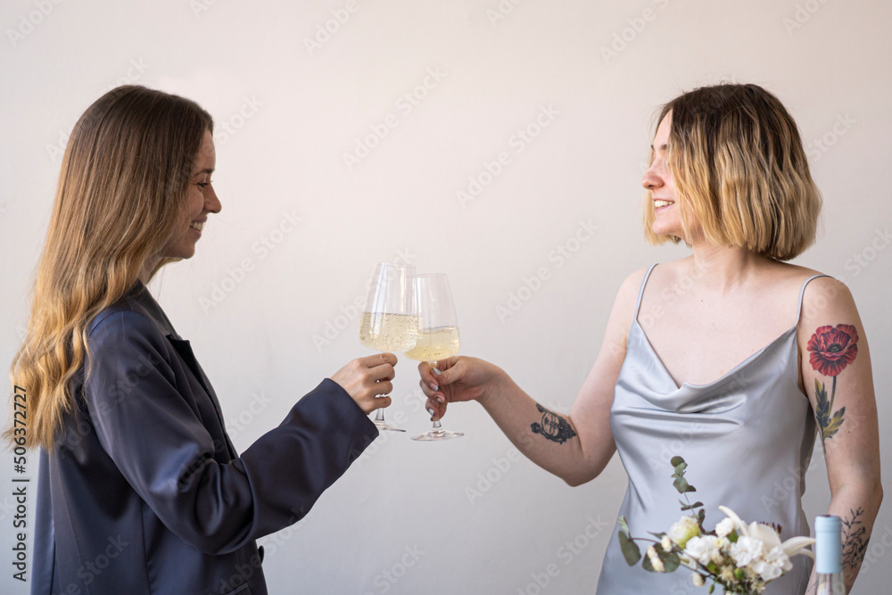 Happy female friends toasting wineglasses in front of wall Happy female friends toasting wineglasses in front of wall