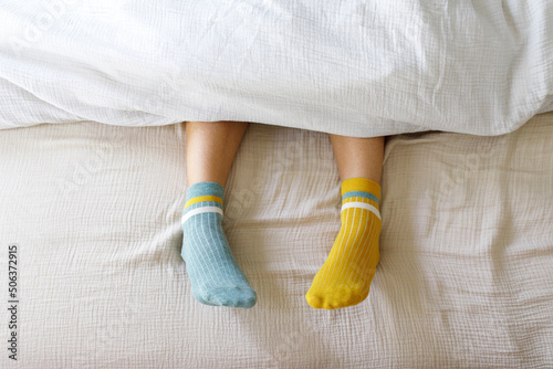 Woman wearing blue and yellow socks in bed at home photo
