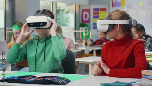 Portrait of schoolkids sitting at desk and putting on vr headset in classroom