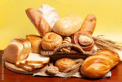 Bread with buns,drying bagels,wheat ears on yellow background. Culinary background
