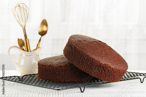 Fotografija Just baked plain Chocolate sponge cake on the cooking iron grid, white table