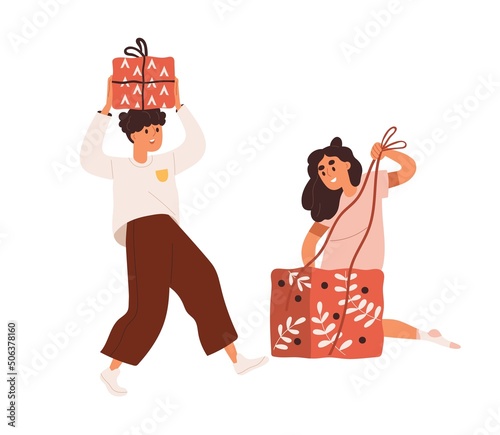 Kids preparing holiday gifts. Children packing present with ribbon and bow. H...