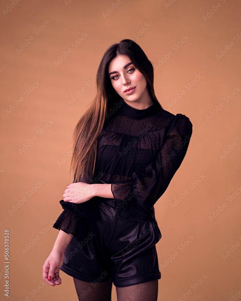 Woman in shorts and black blouse over isolated warm background Woman in shorts and black blouse over isolated warm background