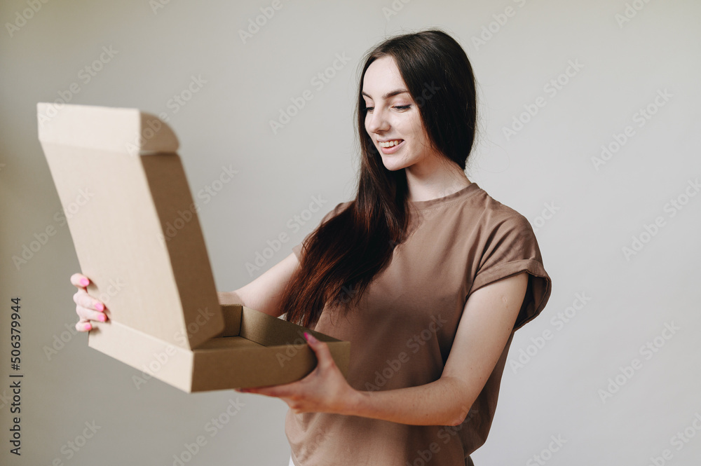 Portrait of a girl in ordinary life and an open cardboard box on the wall, looks into the box. Portrait of a girl in ordinary life and an open cardboard box on the wall, looks into the box.