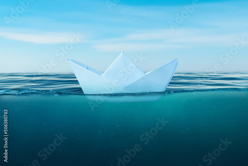 Paper boat on the sea surface. View under the sea. The concept of courage and bravery in life and the risk of making bad decisions that can sink a ship photo