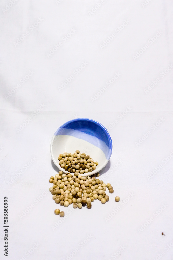 white pepper spilled from porcelain container, isolated on white white pepper spilled from porcelain container, isolated on white