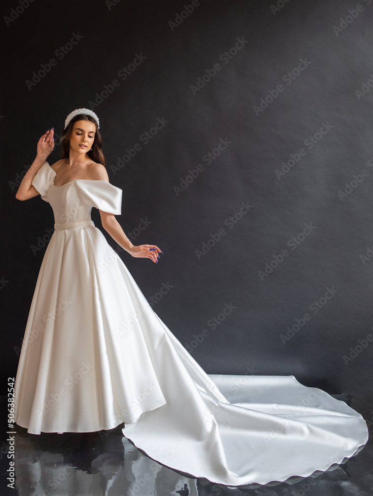 Full length bride portrait. Elegant woman in white wedding dress spinning in beige interior. Full length bride portrait. Elegant woman in white wedding dress spinning in beige interior.