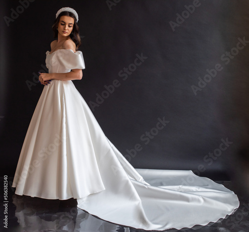 Full length bride portrait. Elegant woman in white wedding dress spinning in beige interior.