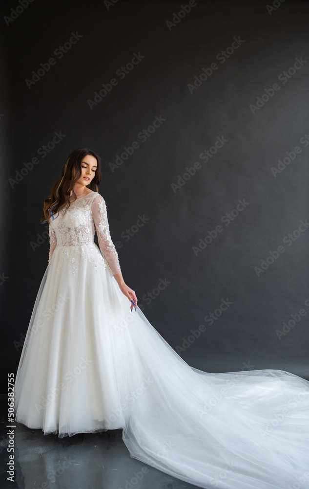 Full length portrait of young beautiful woman wearing white wedding dress. Elegant bride standing and posing