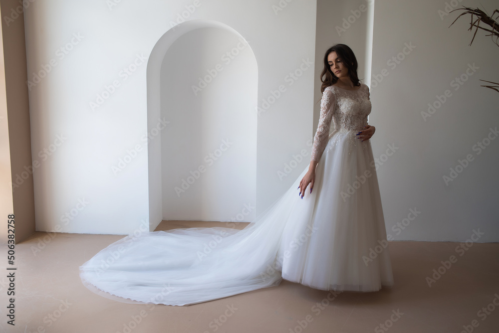 Full length portrait of young beautiful woman wearing white wedding dress. Elegant bride standing and posing Full length portrait of young beautiful woman wearing white wedding dress. Elegant bride standing and posing