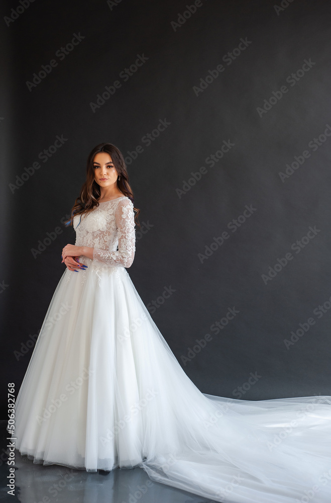 Full length portrait of young beautiful woman wearing white wedding dress. Elegant bride standing and posing