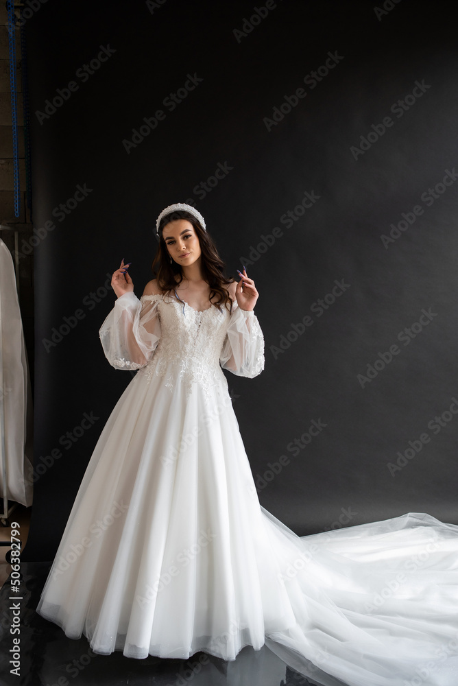 Full length portrait of young beautiful woman wearing white wedding dress. Elegant bride standing and posing