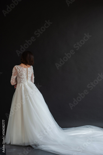 Full length portrait of young beautiful woman wearing white wedding dress. Elegant bride standing and posing