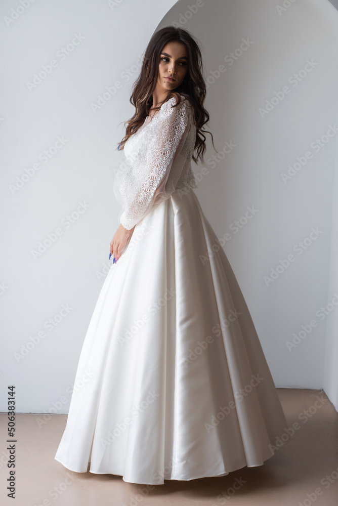 Charming young bride in luxurious wedding dress. Pretty girl in white. Emotions of happiness, laughter and smile, gray background Charming young bride in luxurious wedding dress. Pretty girl in white. Emotions of happiness, laughter and smile, gray background