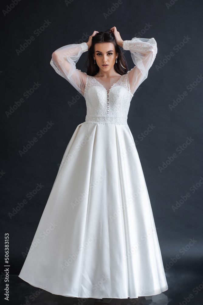 Fototapeta premium Beauty Portrait of bride wearing in wedding dress with voluminous skirt, studio photo. Young attractive bride. Smiling beautiful young bride