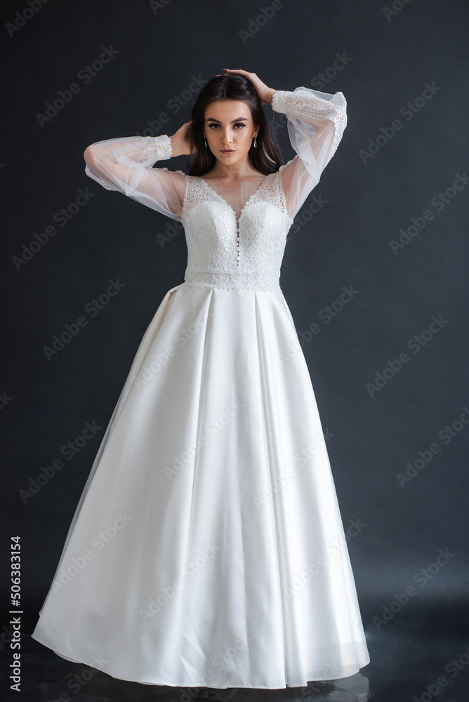 Charming young bride in luxurious wedding dress. Pretty girl in white. Emotions of happiness, laughter and smile, gray background Charming young bride in luxurious wedding dress. Pretty girl in white. Emotions of happiness, laughter and smile, gray background