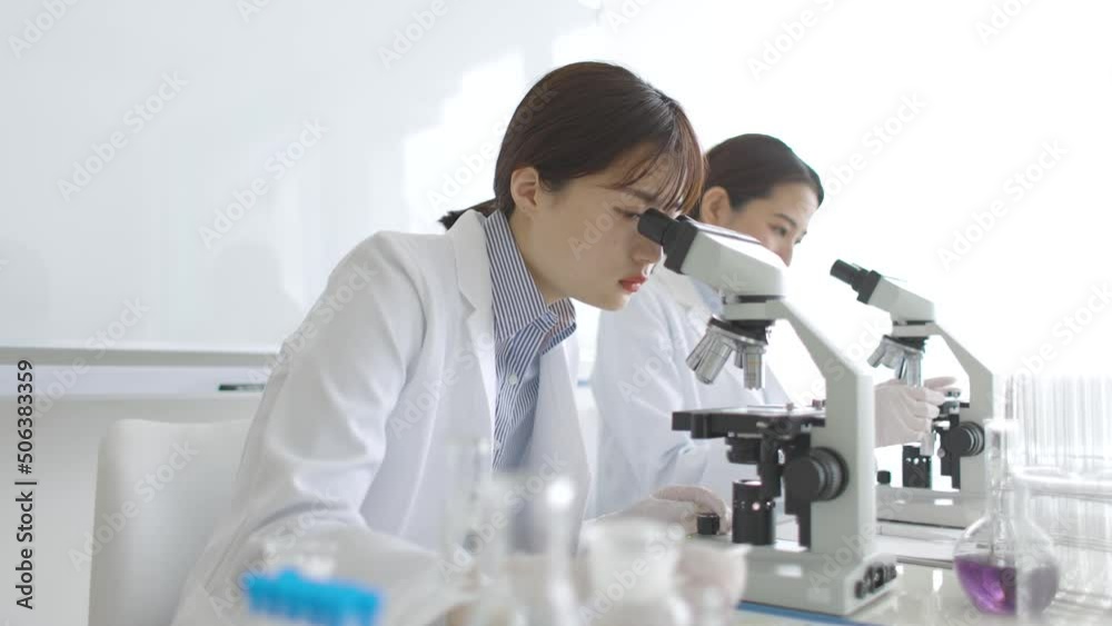 顕微鏡を覗く研究者の女性 顕微鏡を覗く研究者の女性