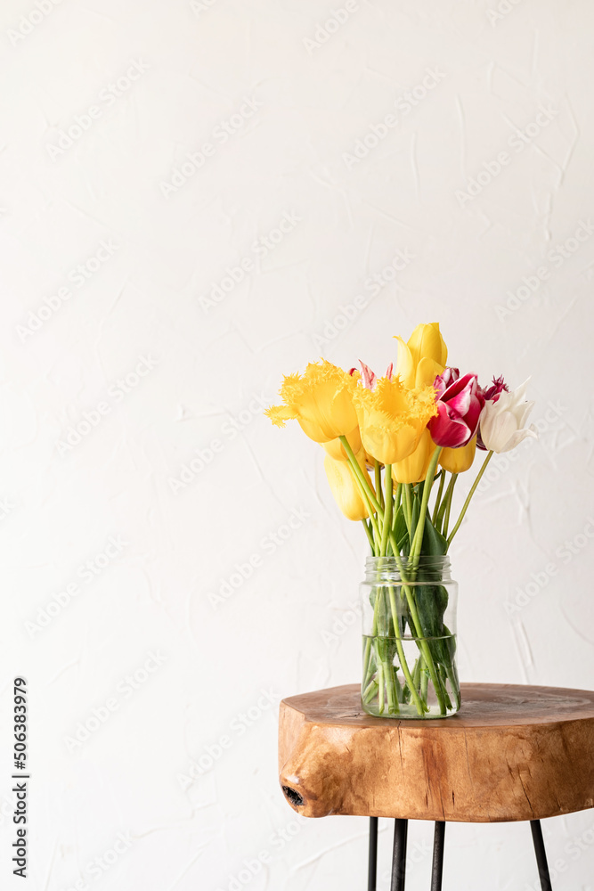 minimal home interior with stylish wooden coffee table and bouquet of fresh tulips