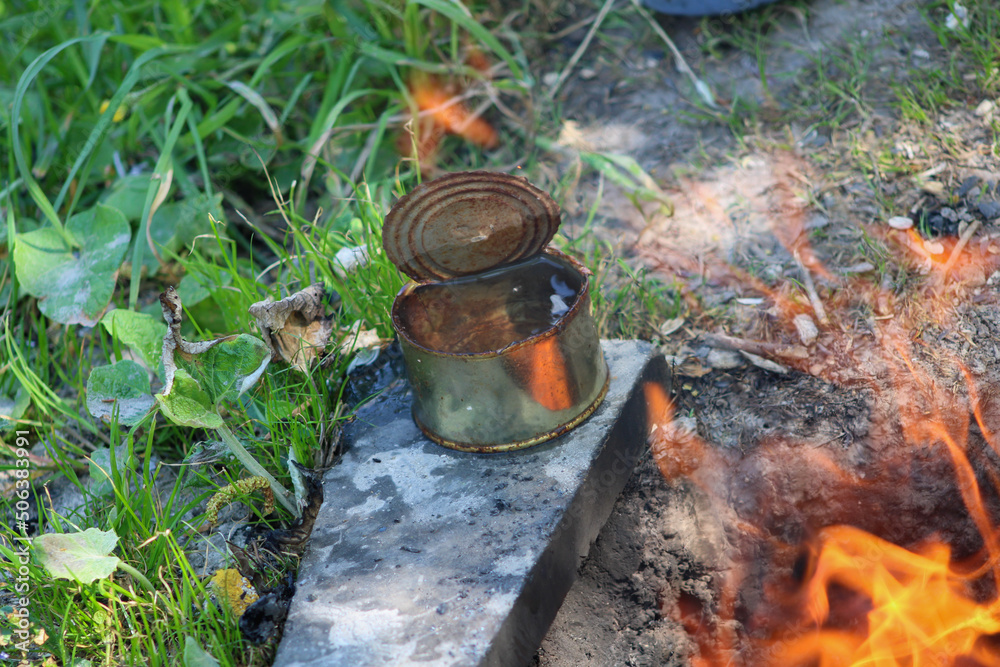 Metal jar of water warming near the fire Metal jar of water warming near the fire