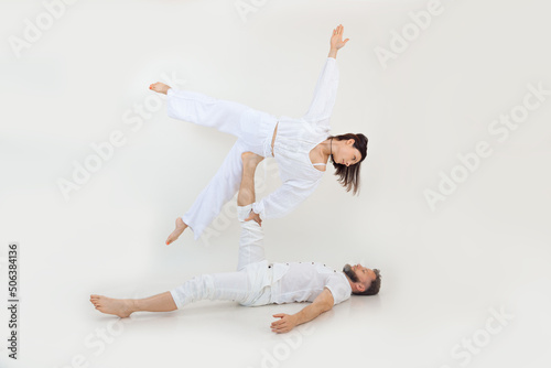 Man and woman, family do sport exercises, fitness and acrobatics yoga. Spirituality and zen meditation. Holding on leg