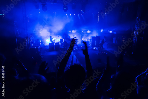 Silhouettes of concert crowd in front of blue stage lights. Fans during a life concert