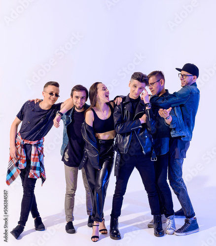 Group of six young boy and girl friends hugging and fooling around and laughing on a white background with blue light