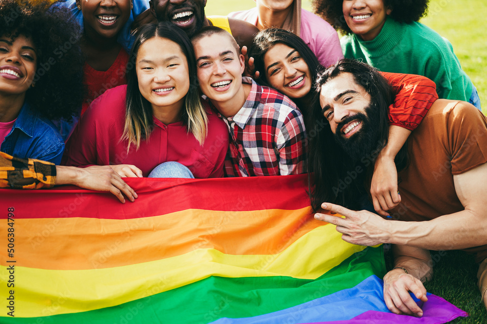 Fototapeta premium Diverse people having fun holding LGBT rainbow flag outdoor